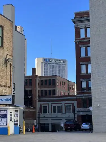 Urban canyons reveal a distant skyscraper under blue skies.